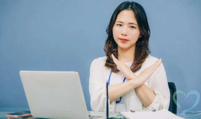 女性が胸元でバツマークを作っている