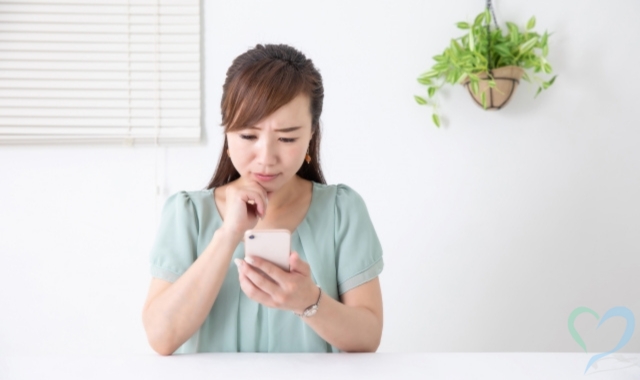 不安そうにスマホ画面を見ている女性