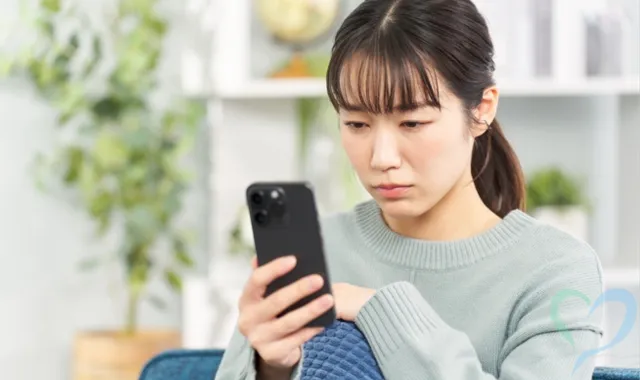 スマホを持ち悩む女性