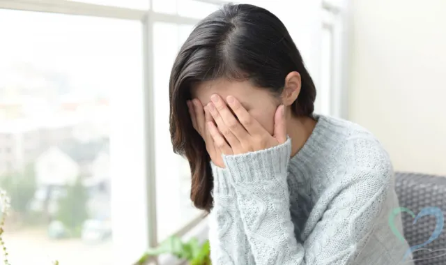 窓際で悩む女性