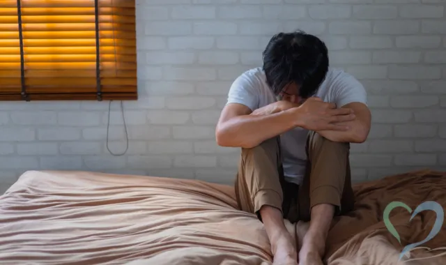 膝を抱える男性